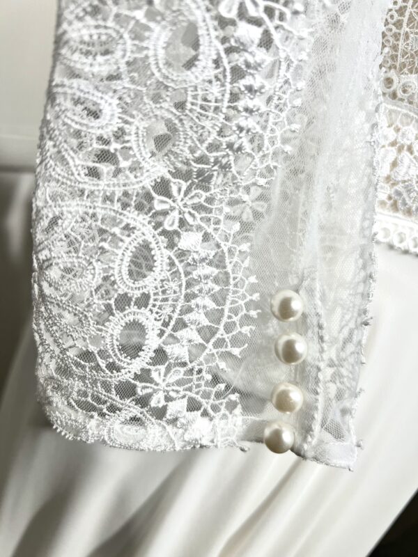 Robe de mariée bohème à manches longues en dentelle dans un jardin intérieur verdoyant