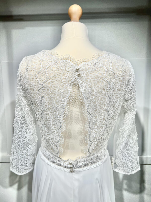 Robe de mariée bohème à manches longues en dentelle dans un jardin intérieur verdoyant