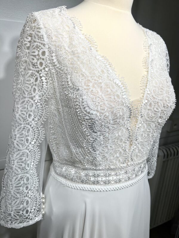 Robe de mariée bohème à manches longues en dentelle dans un jardin intérieur verdoyant