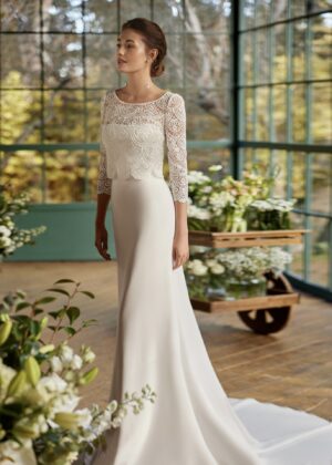 Mariée en robe de mariée en dentelle avec manches trois-quarts, posant dans un cadre floral intérieur