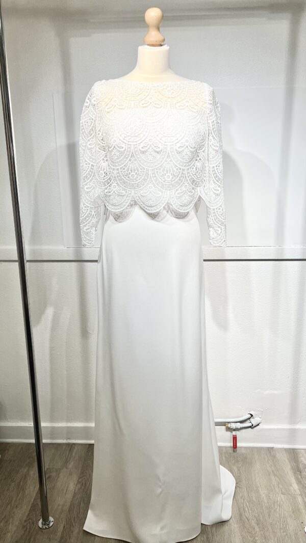 Mariée en robe de mariée en dentelle avec manches trois-quarts, posant dans un cadre floral intérieur