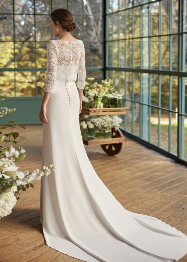 Mariée de dos en robe de mariée avec dos en dentelle et longue traîne, posant dans un cadre lumineux entouré de fleurs