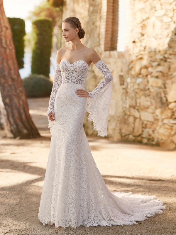 Robe de mariée en dentelle à manches trois-quarts avec détails floraux, avec une mariée élégante en pleine conversation avec un homme en costume beige