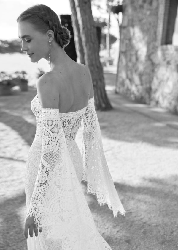 Gros plan en noir et blanc d'une mariée en robe de dentelle, avec des boucles d'oreilles en perles et un chignon sophistiqué