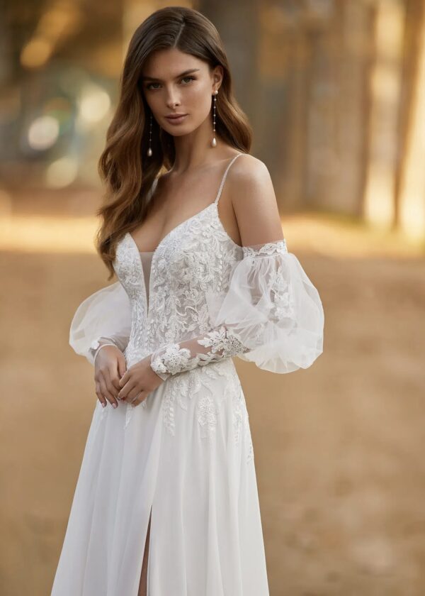 Gros plan sur le corsage en dentelle et les manches transparentes en tulle d'une robe de mariée bohème à décolleté plongeant.