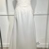 Cette robe de mariée allie minimalisme et élégance avec son corsage ajusté à col carré et sa jupe fluide prolongée d’une traîne légère. Son design épuré s’harmonise parfaitement avec un cadre méditerranéen raffiné, idéal pour une mariée au style intemporel.