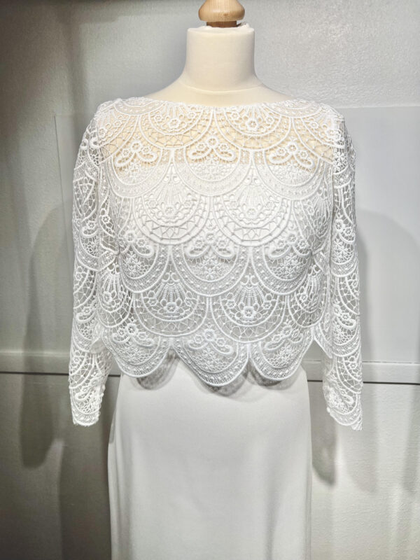 Mariée en robe de mariée en dentelle avec manches trois-quarts, posant dans un cadre floral intérieur