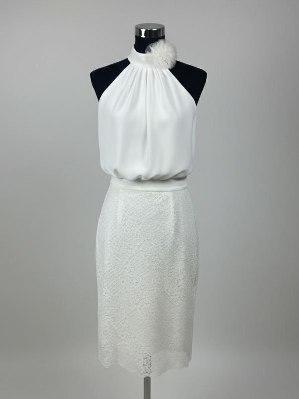 Robe de mariée courte minimaliste en dentelle, silhouette droite, jupe mi-longue en dentelle fine, top fluide à col montant, drapé élégant et fleur en tissu sur le côté, parfaite pour une cérémonie civile ou une réception décontractée.