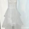 Robe de mariée bustier en tulle blanc, corsage texturé, volants superposés et base légèrement transparente, pour une silhouette aérienne et romantique.