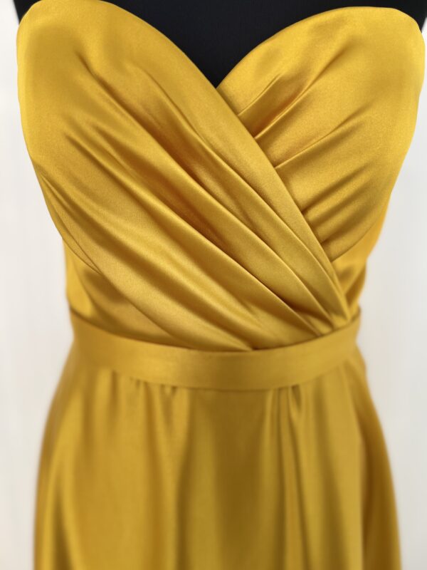 Robe de cocktail longue en satin jaune, sans manches, ajustée au buste avec une coupe fluide et un tombé élégant jusqu’au sol.