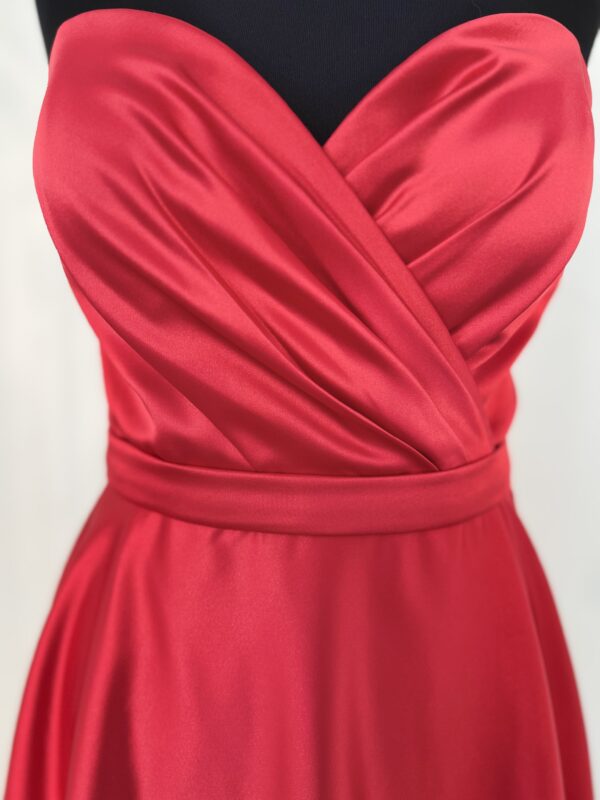 Robe de cocktail courte en satin rouge, avec un bustier cœur drapé et une ceinture fine, offrant une coupe fluide et moderne.
