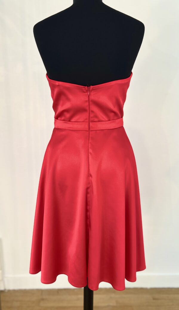 Robe de cocktail courte en satin rouge, avec un bustier cœur drapé et une ceinture fine, offrant une coupe fluide et moderne.