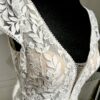 Robe de mariée avec bustier en tulle illusion, broderies florales blanches, décolleté en dentelle et manches cap.