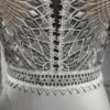 Robe de mariée Tina d’Angeola en tulle illusion avec broderies florales, décolleté en dentelle et ceinture géométrique.