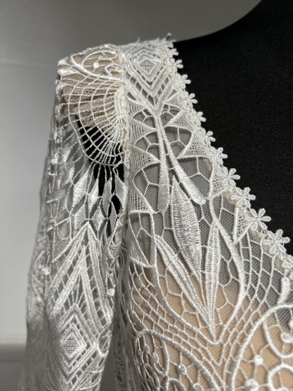 Robe de mariée Tina d’Angeola en tulle illusion avec broderies florales, décolleté en dentelle et ceinture géométrique.