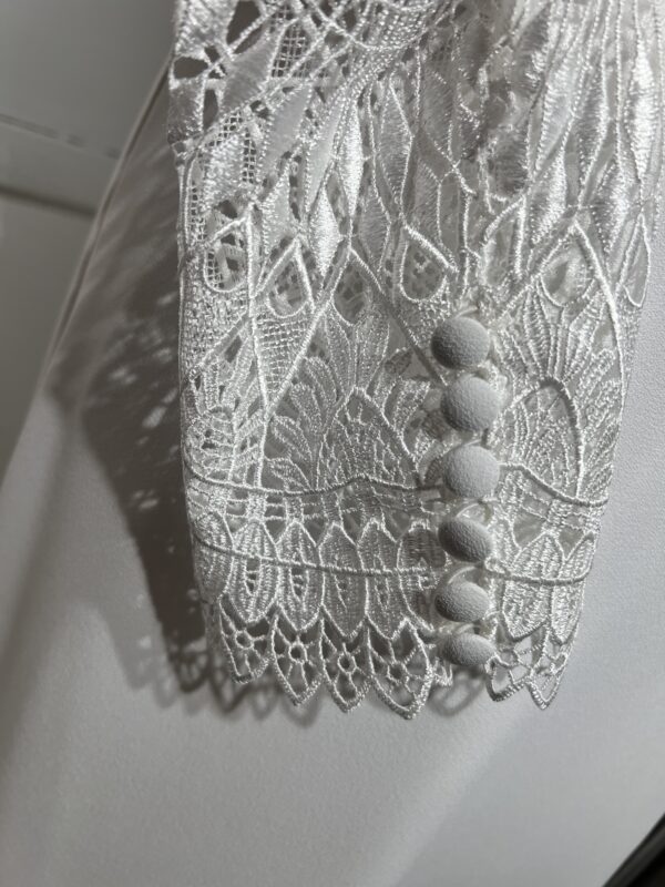 Robe de mariée Tina d’Angeola en tulle illusion avec broderies florales, décolleté en dentelle et ceinture géométrique.