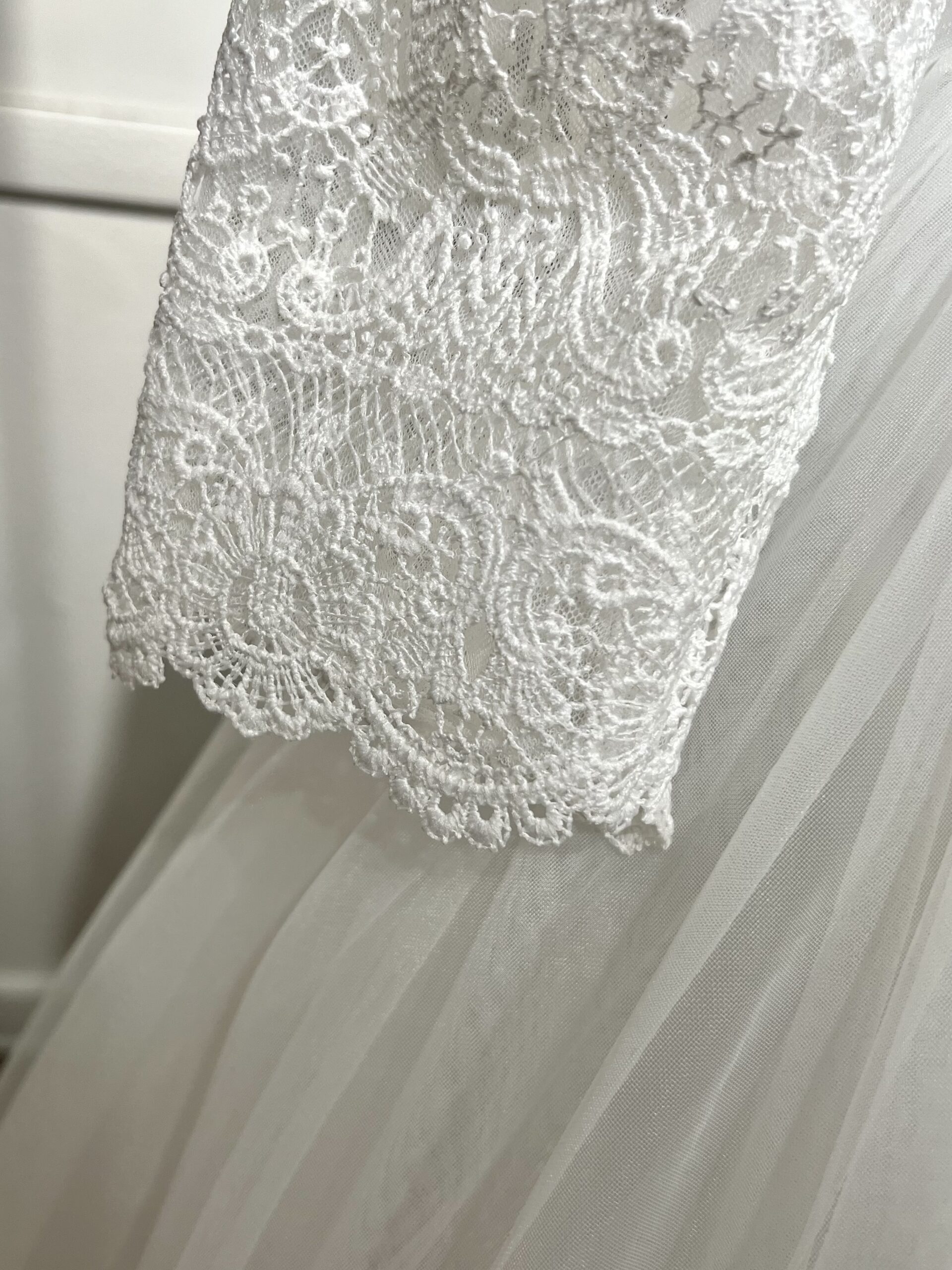 Robe de mariée élégante, manches longues en dentelle, décolleté en V, jupe en tulle fluide.