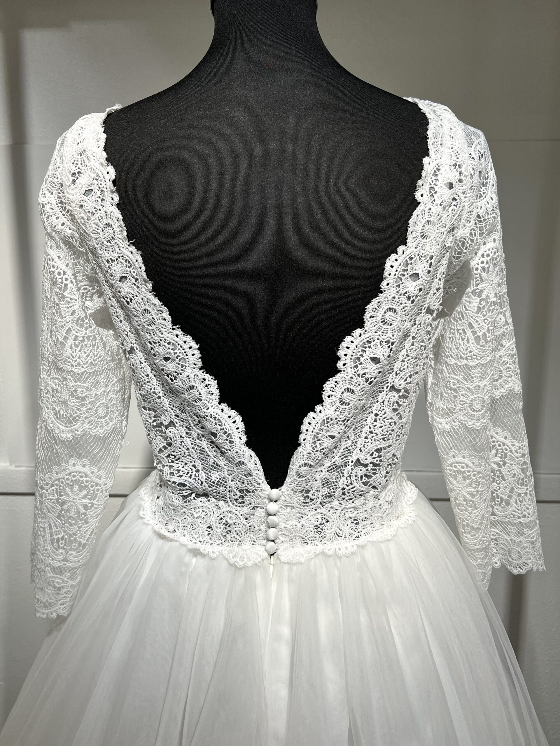 Robe de mariée élégante, manches longues en dentelle, décolleté en V, jupe en tulle fluide.