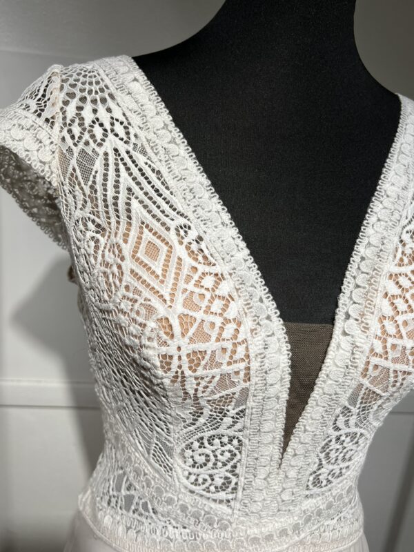 Robe de mariée moderne avec bustier en dentelle blanche, manches courtes, décolleté en V et jupe longue fluide en tissu vaporeux