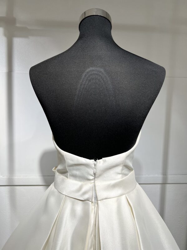 Robe de mariée Divina Sposa coupe princesse en satin blanc, bustier cœur sans bretelles, ceinture à nœud et jupe fluide jusqu’au sol.