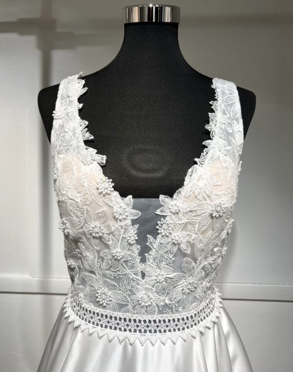 La robe de mariée Tiara avec décolleté en V, bustier en dentelle, ceinture perlée et jupe fluide en satin