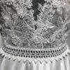 La robe de mariée Tiara avec décolleté en V, bustier en dentelle, ceinture perlée et jupe fluide en satin