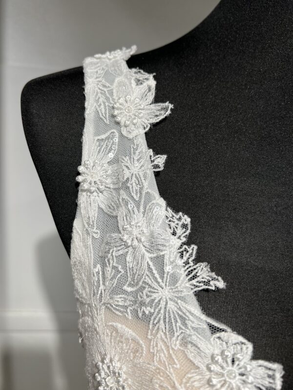 La robe de mariée Tiara avec décolleté en V, bustier en dentelle, ceinture perlée et jupe fluide en satin