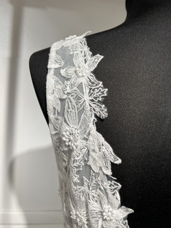 La robe de mariée Tiara avec décolleté en V, bustier en dentelle, ceinture perlée et jupe fluide en satin