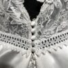 La robe de mariée Tiara avec décolleté en V, bustier en dentelle, ceinture perlée et jupe fluide en satin