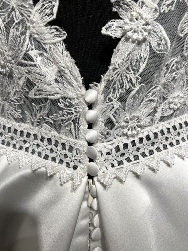 La robe de mariée Tiara avec décolleté en V, bustier en dentelle, ceinture perlée et jupe fluide en satin