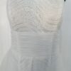 Robe de mariée bustier en tulle blanc, corsage texturé, volants superposés et base légèrement transparente, pour une silhouette aérienne et romantique.