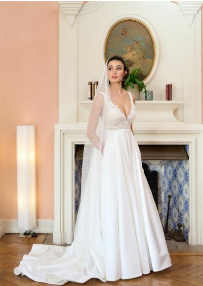 La robe de mariée Tiara avec décolleté en V, bustier en dentelle, ceinture perlée et jupe fluide en satin