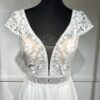 Robe de mariée avec bustier en tulle illusion, broderies florales blanches, décolleté en dentelle et manches cap.