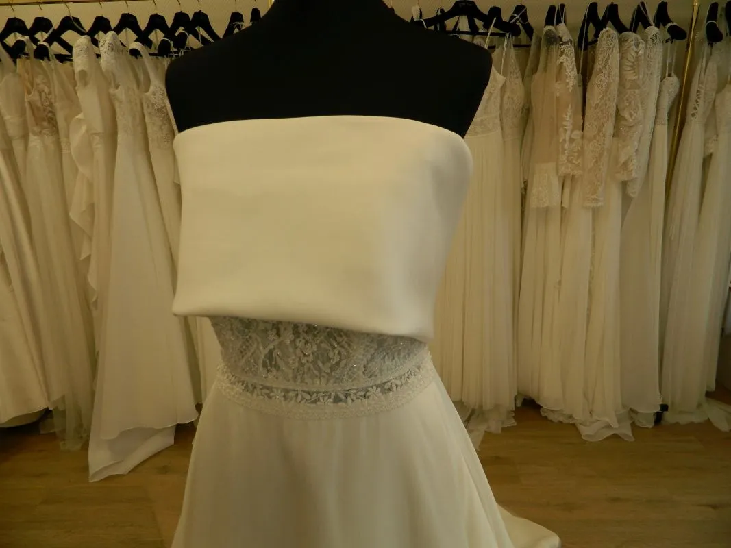 Gros plan sur le bustier bandeau en mikado et la ceinture en dentelle de la robe de mariée Syma d'Aire Barcelona.