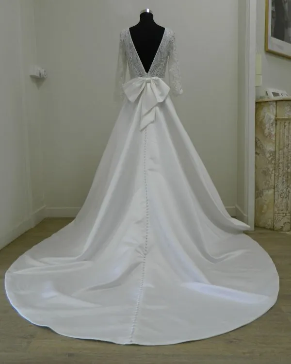 Robe de mariée princesse en mikado Suna par Aire Barcelona vue de dos avec décolleté en V, grand nœud et longue traîne.
