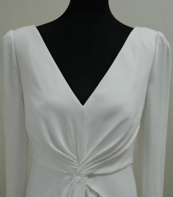 Détail en gros plan du bustier en crêpe avec décolleté en V et nœud drapé de la robe de mariée Salvia d'Aire Barcelona au showroom de Tours.