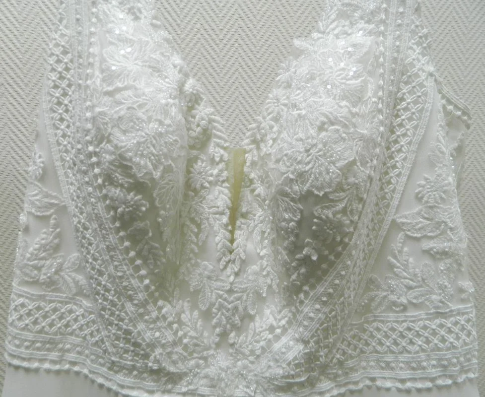 Gros plan sur le bustier en dentelle florale et le décolleté en V plongeant de la robe de mariée trapèze grande taille Galyn de Martha Blanc.