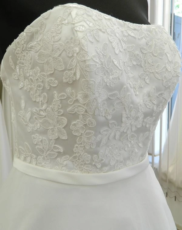Gros plan sur le bustier cœur en dentelle florale blanche de la robe de mariée courte NC2924 de Nana Couture sur mannequin.
