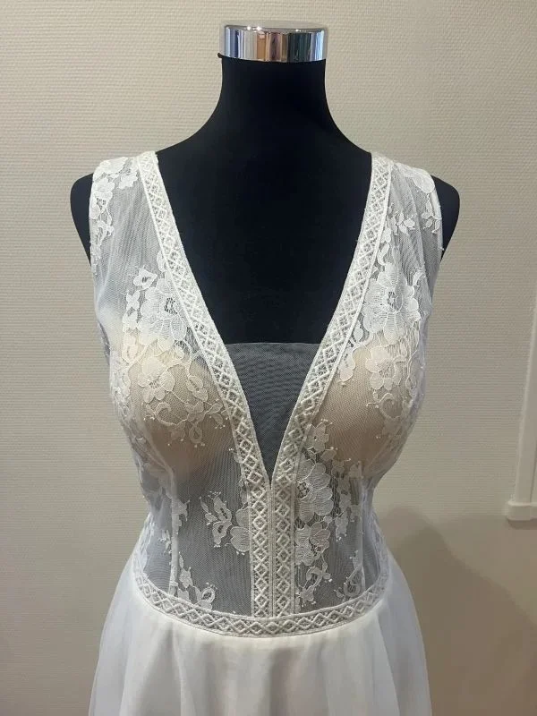 Gros plan sur le bustier effet illusion en dentelle florale transparente avec décolleté plongeant en V et coques nudes de la robe de mariée Kasmira par Te Amo.