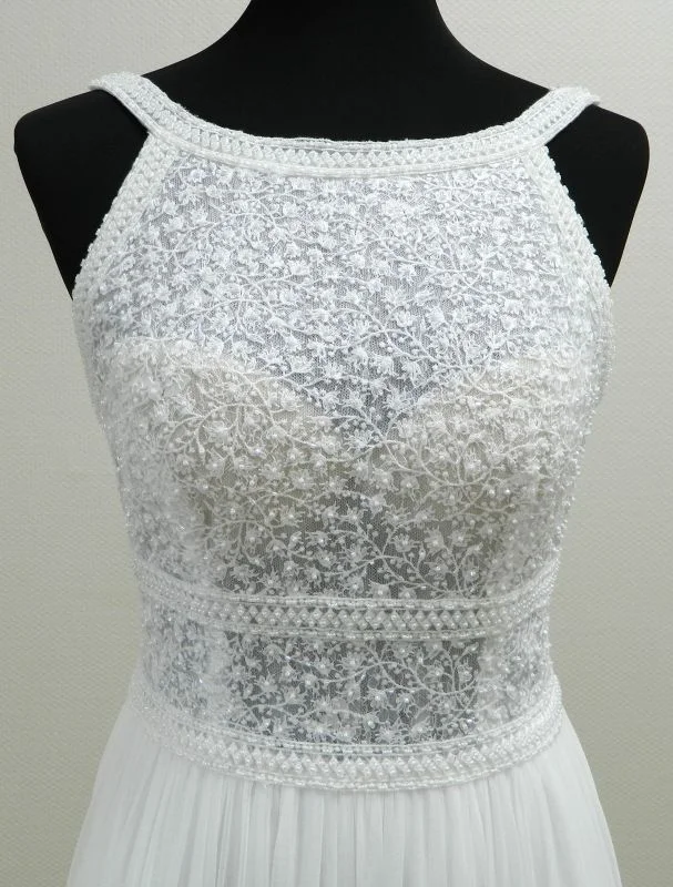 Gros plan technique de face sur le bustier col licou en dentelle florale givrée de sequins et la double ceinture perlée ajourée de la robe de mariée Kalina de Rosa Clará.