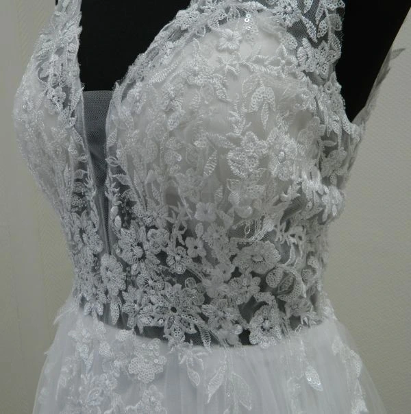 Détail en gros plan du bustier brodé de dentelle florale et de paillettes scintillantes de la robe de mariée MARFIL 8JB1 au showroom de Tours.