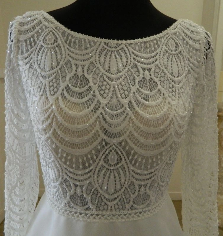 Détail en gros plan du bustier en dentelle perlée et encolure bateau de la robe de mariée Sira d'Aire Barcelona au showroom de Tours.