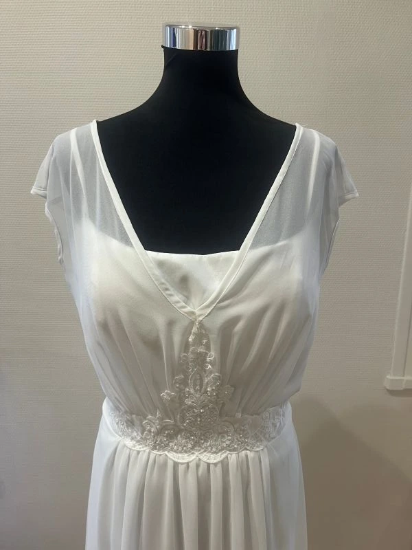 Gros plan sur le bustier drapé en mousseline et la ceinture brodée perlée de la robe de mariée courte blanche NY2779 par Fashion New York.