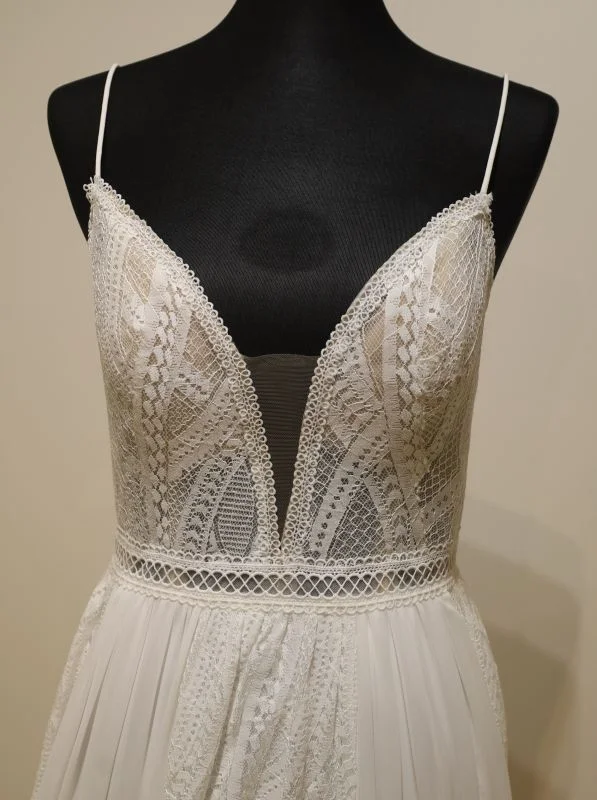 Gros plan technique du corsage en dentelle et du décolleté plongant bikini de la robe de mariée Adore 11233 Justin Alexander sur mannequin.