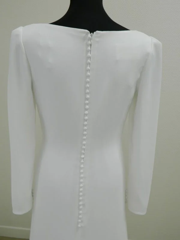 Gros plan sur le dos boutonné en crêpe et les manches longues de la robe de mariée fourreau Salvia d'Aire Barcelona au showroom de Tours.
