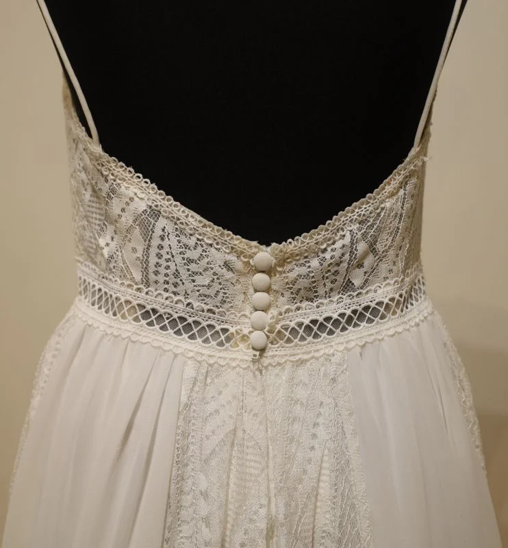 Gros plan technique du dos nu en dentelle et des boutons de finition de la robe de mariée Adore 11233 Justin Alexander sur mannequin.