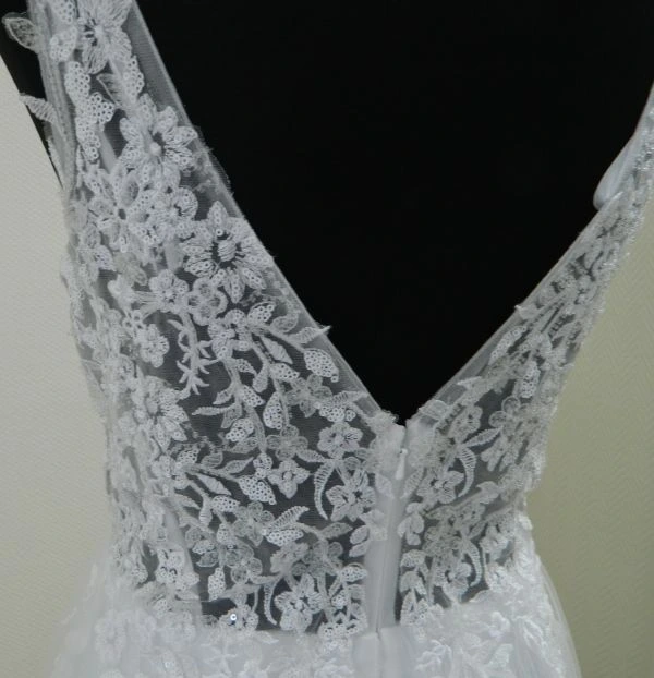 Gros plan du décolleté en V dans le dos en dentelle florale et paillettes scintillantes de la robe de mariée MARFIL 8JB1 au showroom de Tours.