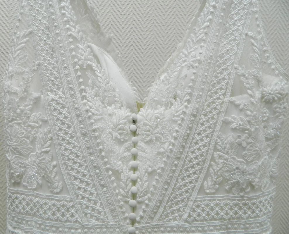 Gros plan sur le décolleté dos nu en V et la rangée de boutons délicats de la robe de mariée trapèze grande taille Galyn de Martha Blanc.