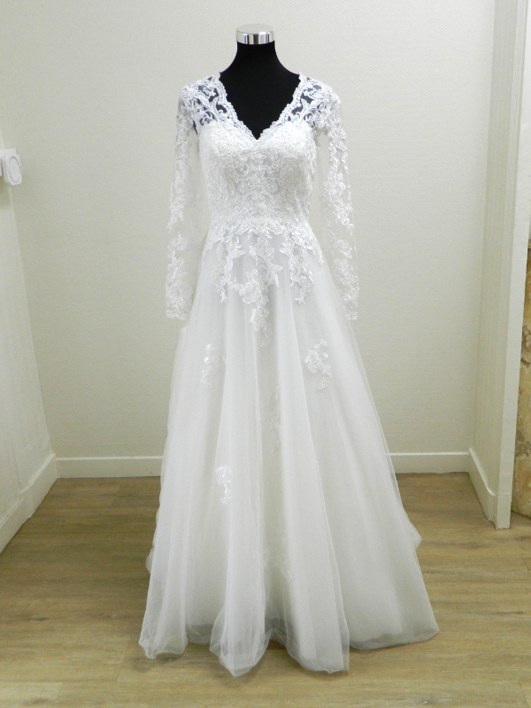 Robe de mariée princesse Lovely 23419 sur portant, vue de face complète, présentant sa coupe évasée et ses manches longues en dentelle.