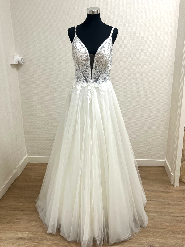Vue de face de la robe de mariée princesse Très Chic 23419 sur portant, montrant le bustier en dentelle perlée et la jupe en tulle.